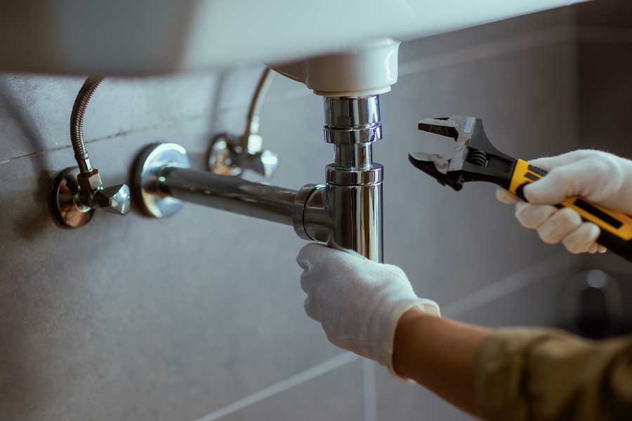 Plumber tightening drain pipe during sink installation in Lake Oswego